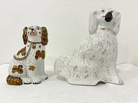 Front view of both Staffordshire dog figurines highlighting size difference and decorative details