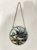 Front view of round painted glass window hanging with chain