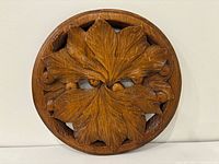 Front view of round mahogany carving with leaf motif