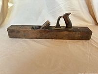 Side view of wooden jointer plane showing tote handle, wedge and iron