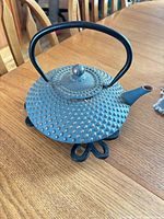Blue cast iron teapot on trivet, showing color, texture and overall design