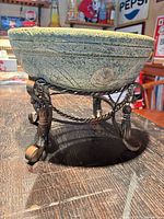 Side view of ceramic bowl on stand showing embossed swirl motif and stand details