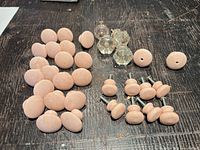 Group of ceramic knobs, glass pulls, and mounted knobs laid out on dark surface