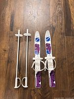 Full view of two white Komperdell Spike skis with bindings and two white ski poles