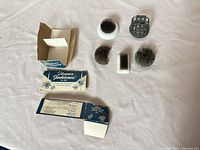 Overhead view of all five floral frogs with two small empty boxes for scale