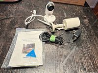 Lot overview showing both cameras, manual, power adapter, cable and mounting hardware