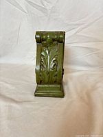 Front view showing acanthus leaf and scroll design on painted green corbel