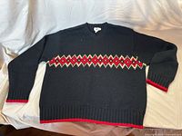 Full front view of black sweater showing argyle stripe, cuffs and hem