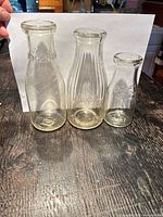Three vintage glass milk bottles standing side by side