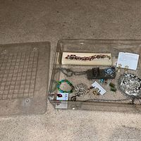 Overview of jewelry pieces in clear bin with lid