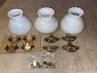 Group shot: three milk glass shades, drawer pulls on card, loose pulls, bag of hooks