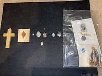 All items laid out on black background including cross, small pendants and sealed packet