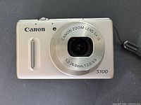 Front view of Canon PowerShot S100 showing lens, branding and body