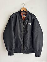 Full front view of black bomber jacket on hanger
