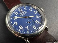 Close view of dial showing blue face, numerals, brand and sub-seconds