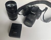 Camera body with 18-55 mm lens attached, 75-300 mm lens and charger shown