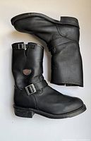 Side view of both black leather engineer boots showing buckles and shield patch