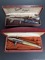 Both airbrushes opened in their original cases showing handles and accessories