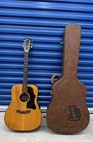 Full front view of guitar next to case