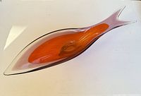 Top view of elongated fish-shaped orange cased glass ashtray