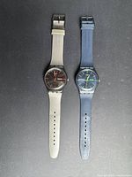 Front view of both Swatch watches on black background