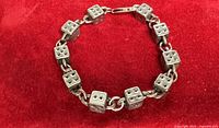 Full view of bracelet in closed circle showing dice links and clasp