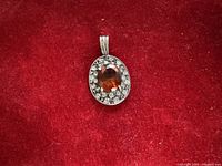 Front view of oval sterling pendant showing gemstone and halo