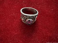 Front view showing faceted purple gemstone and ornate filigree band