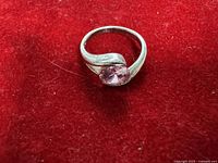 Front view of sterling silver ring with pink stone on red background