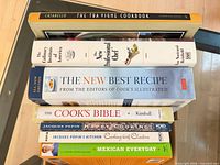 Stack of seven cookbooks showing all titles on spines