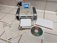 Front view of Canon Selphy DS810 printer with manual, CD, paper pack and print tray