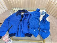 Front view of both the Eddie Bauer jacket and ski vest on table