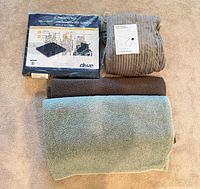All four items grouped: packaged Gel-U-Seat cushion, grey electric blanket rolled, teal sherpa blanket, brown fleece blanket