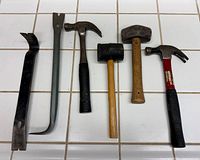 Six tools laid out: two pry bars, two claw hammers, rubber mallet, engineer’s hammer