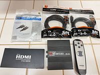 All items laid out: two sealed 8-ft HDMI cables, one sealed 10-ft HDMI cable, two HDMI switch boxes and remote