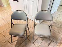 Front view of two tan Cosco padded folding chairs