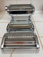 Front view of chrome Marcato Atlas 150 pasta roller with two cutter attachments stacked