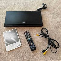 Top view of Blu-ray player, remote, A/V cable, and manual