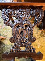 Close-up of ornate carved mask and foliate motif on base