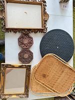 All seven items laid out: ornate frames, square mirror, wood trivets, rattan trays, round plastic tray