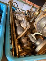 Blue bin filled with brass-plated lighting parts including arms, rods, canopies and hardware
