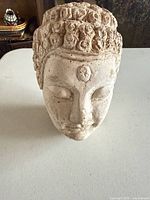 Front view of plaster Buddha head on table