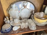 Shelf view showing multiple clear pressed crystal pieces; compote and sugar bowl visible right side