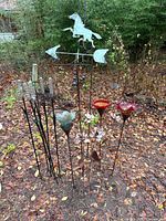 All garden stakes grouped outdoors showing horse weathervane, flower stakes, and glass-topped stakes