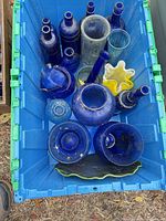 Blue tote with multiple cobalt blue bottles, vases, bowls and one yellow ruffled bowl