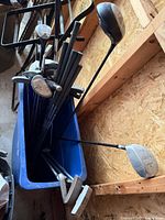 Overview of mixed golf clubs in blue plastic tote