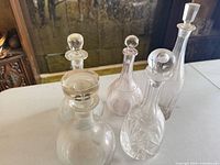 Group of five clear glass decanters/cruets showing variety of forms and stoppers