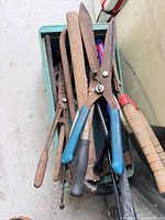 Green bin holding hedge shears, files, rasps and other hand tools