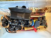 Top view of storage bin showing binoculars, case, kaleidoscope tubes and plastic accessories