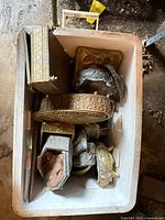 Top view of container holding assorted metal decorative hardware pieces